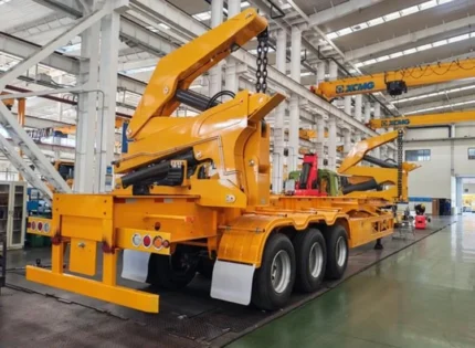 Self-loading mechanism lifting a 40ft container on trailer bed