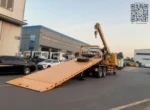 Flatbed tow truck lifting disabled vehicle